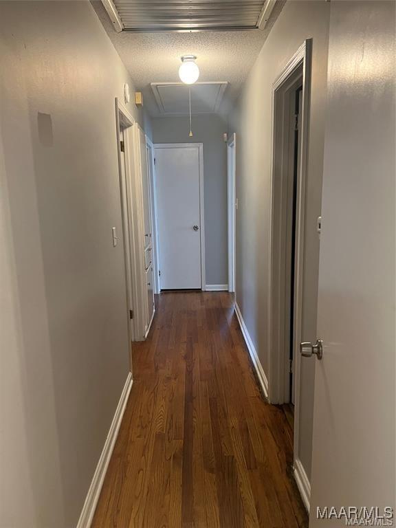 hall featuring a textured ceiling and dark wood-type flooring