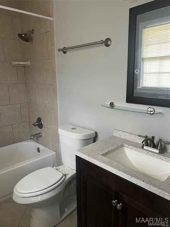 full bathroom featuring tile patterned flooring, tiled shower / bath combo, toilet, and vanity