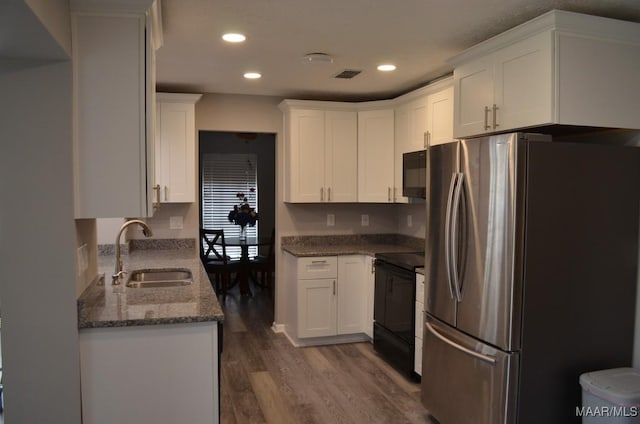 kitchen with dark stone counters, dark wood-type flooring, sink, black appliances, and white cabinets