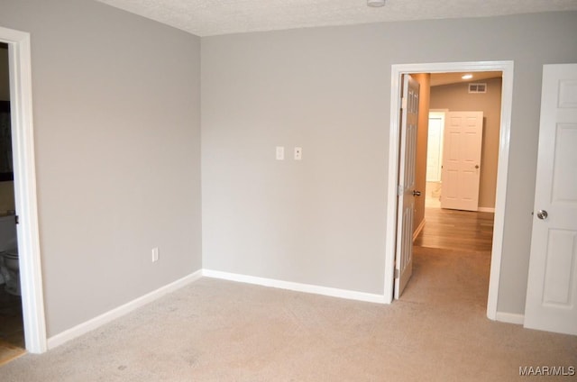 unfurnished bedroom with light carpet and a textured ceiling