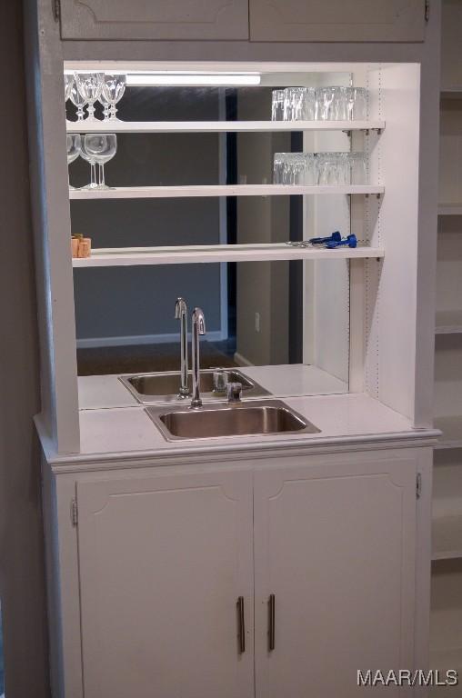 bar with white cabinetry and sink