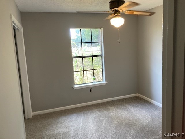 spare room with a textured ceiling, carpet floors, a wealth of natural light, and ceiling fan