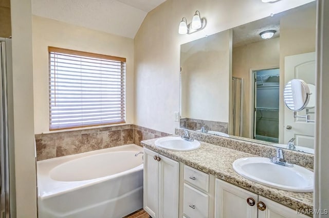 bathroom with a textured ceiling, separate shower and tub, vanity, and lofted ceiling