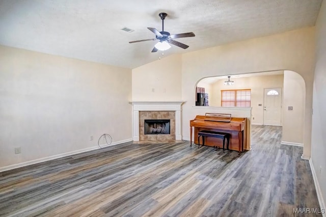 unfurnished living room with lofted ceiling, hardwood / wood-style flooring, ceiling fan, a fireplace, and a textured ceiling