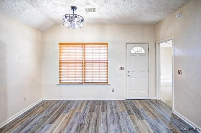 entryway featuring a textured ceiling, wood-type flooring, lofted ceiling, and a notable chandelier