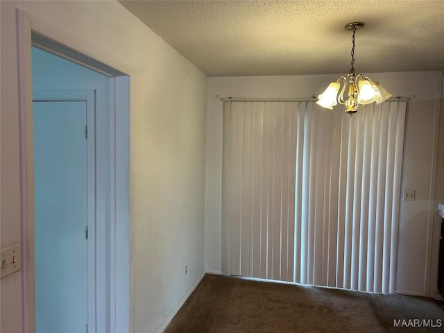 unfurnished dining area featuring carpet flooring, a textured ceiling, and a chandelier