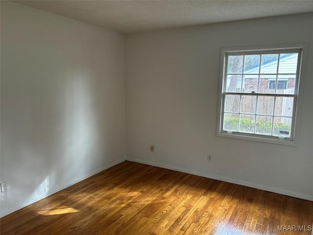 spare room featuring hardwood / wood-style floors, plenty of natural light, and a textured ceiling