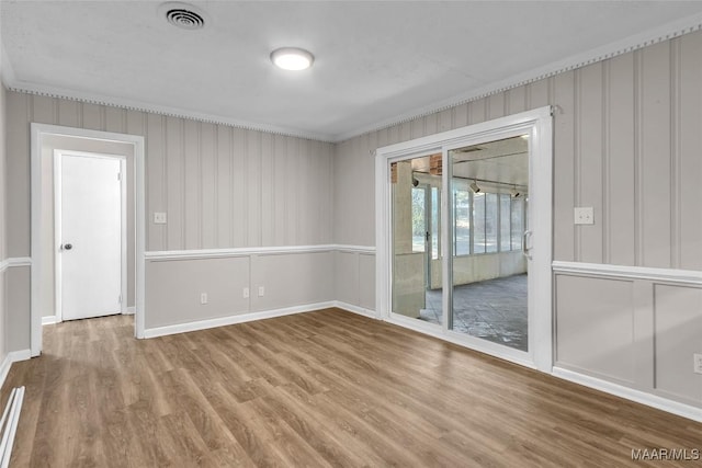 spare room featuring wood-type flooring and ornamental molding