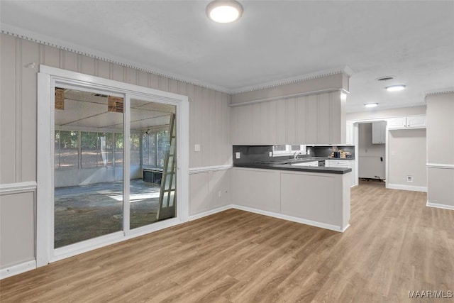 kitchen with white cabinets, kitchen peninsula, light hardwood / wood-style flooring, and sink