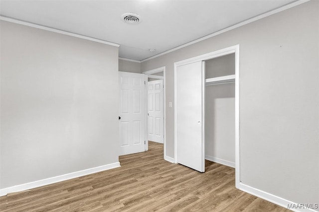 unfurnished bedroom with a closet, crown molding, and light hardwood / wood-style flooring