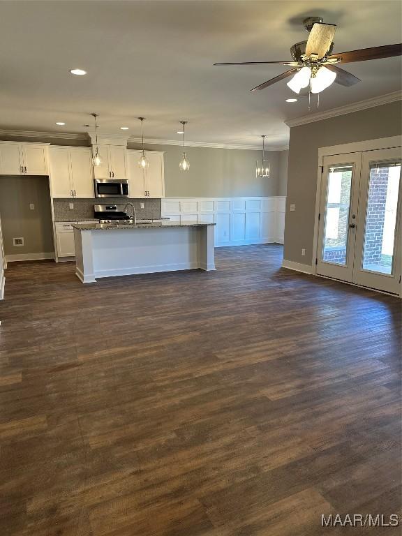 kitchen featuring dark wood-type flooring, stainless steel appliances, dark stone countertops, decorative light fixtures, and white cabinets