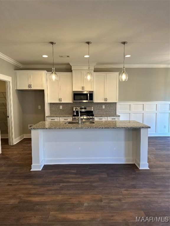 kitchen featuring white cabinets, pendant lighting, stainless steel appliances, and dark stone counters