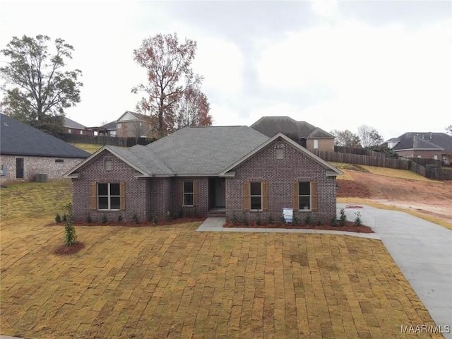 view of front of property featuring a shingled roof, fence, and brick siding