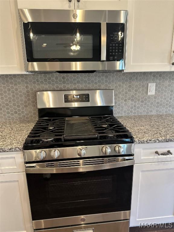 kitchen featuring light stone countertops, tasteful backsplash, white cabinetry, and stainless steel appliances