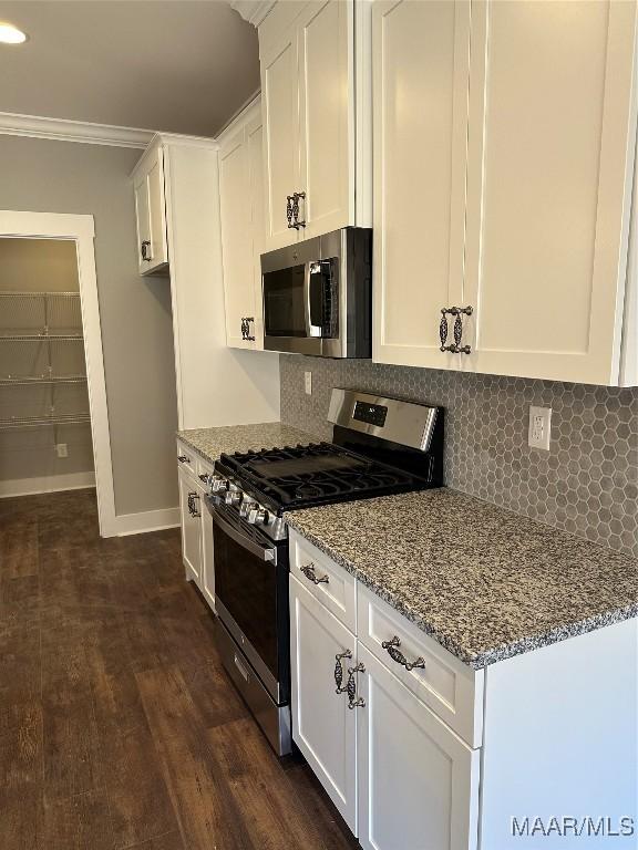 kitchen featuring decorative backsplash, appliances with stainless steel finishes, stone countertops, ornamental molding, and white cabinets