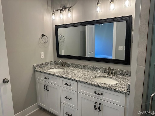 full bathroom featuring double vanity, a sink, and baseboards