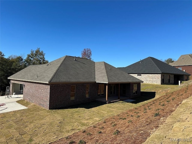 back of house featuring a yard, brick siding, and a patio