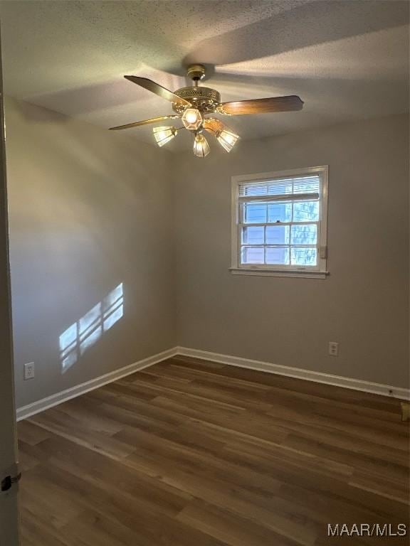 spare room with a textured ceiling, ceiling fan, and dark wood-type flooring