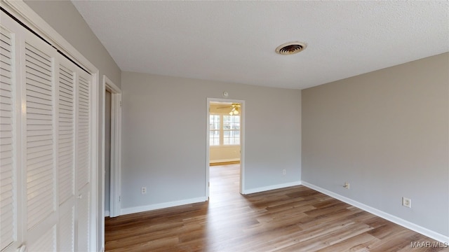 unfurnished bedroom featuring a closet, a textured ceiling, and hardwood / wood-style flooring