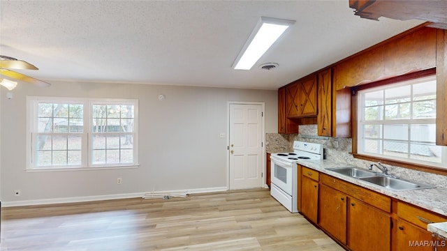 kitchen with decorative backsplash, white electric range oven, a textured ceiling, sink, and light hardwood / wood-style floors