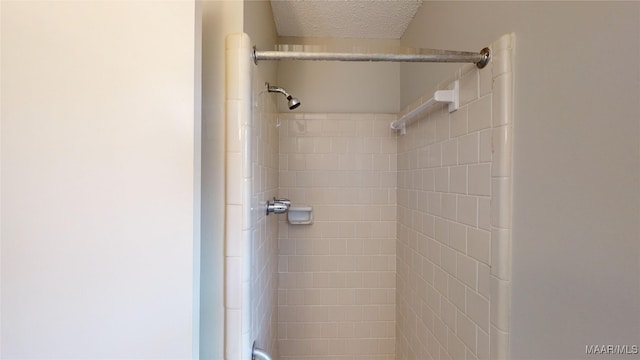 bathroom featuring a tile shower and a textured ceiling