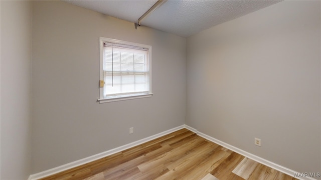 empty room with a textured ceiling and light wood-type flooring