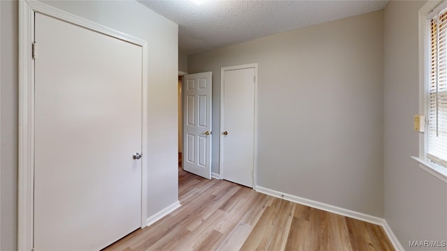 unfurnished bedroom featuring light wood-type flooring and a textured ceiling