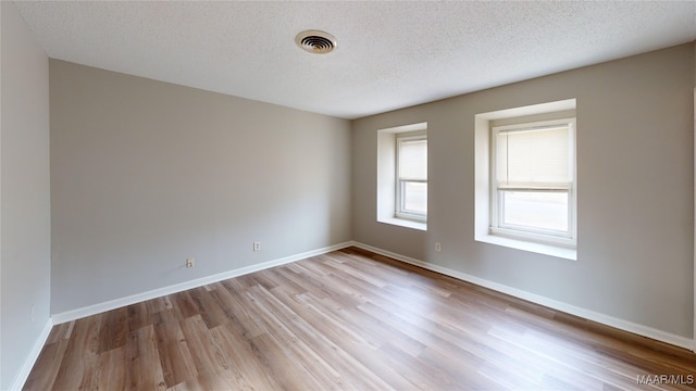 empty room with a textured ceiling and light wood-type flooring