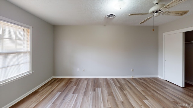 unfurnished bedroom featuring a textured ceiling, a closet, light hardwood / wood-style flooring, and ceiling fan