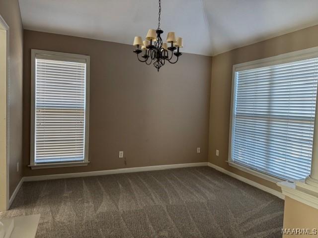 empty room featuring plenty of natural light, a chandelier, and dark colored carpet