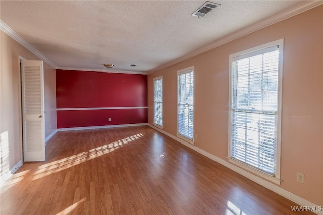 unfurnished room with crown molding, a textured ceiling, and hardwood / wood-style flooring