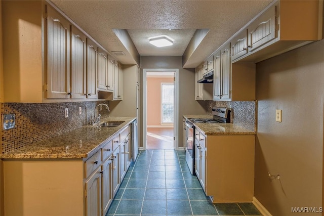 kitchen featuring sink, tasteful backsplash, a textured ceiling, dark tile patterned flooring, and appliances with stainless steel finishes