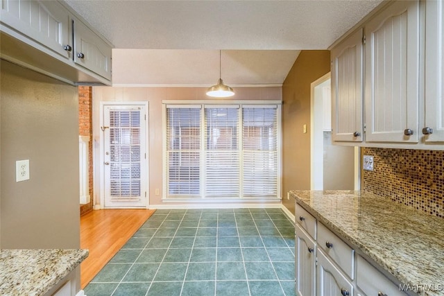 kitchen with pendant lighting, backsplash, vaulted ceiling, hardwood / wood-style flooring, and a textured ceiling