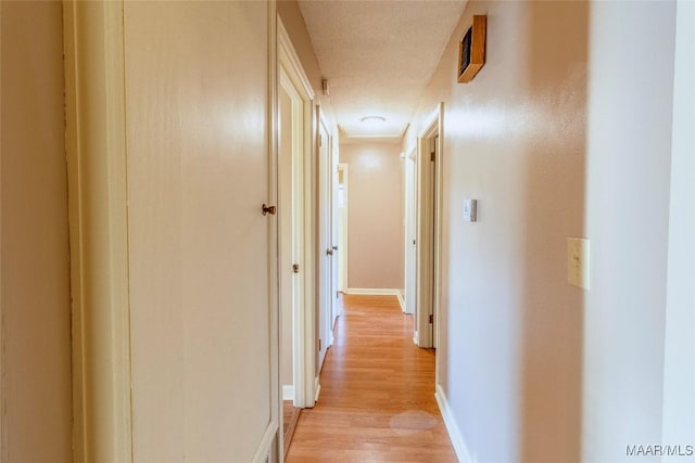 hall featuring light hardwood / wood-style floors and a textured ceiling