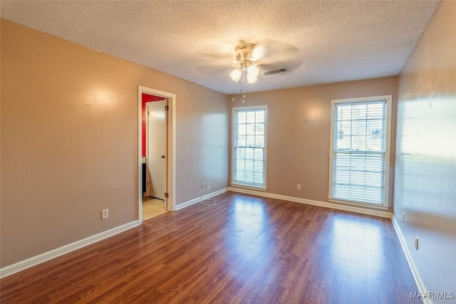 empty room featuring hardwood / wood-style floors, ceiling fan, and a wealth of natural light