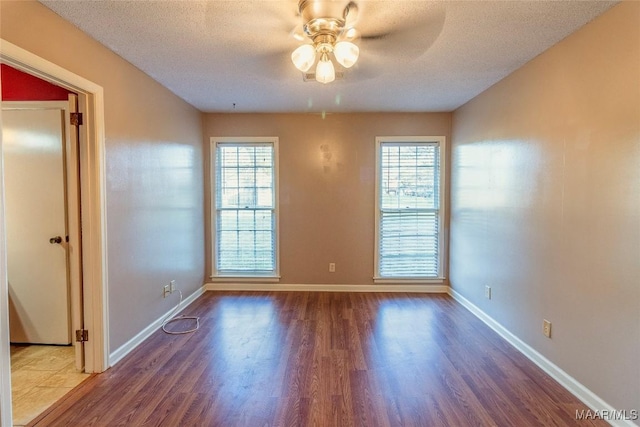 spare room featuring a healthy amount of sunlight, a textured ceiling, and hardwood / wood-style flooring