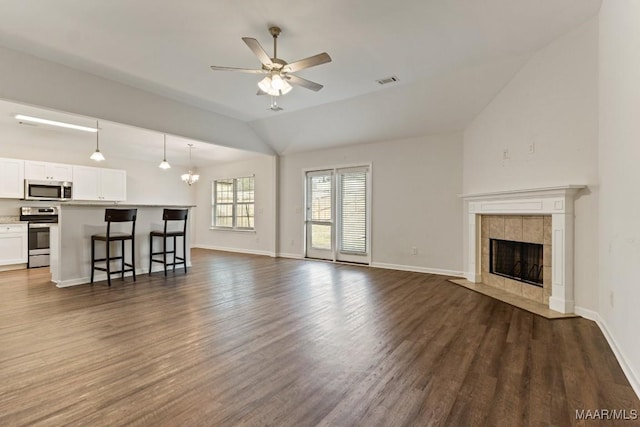 unfurnished living room featuring a fireplace, ceiling fan with notable chandelier, dark hardwood / wood-style floors, and lofted ceiling