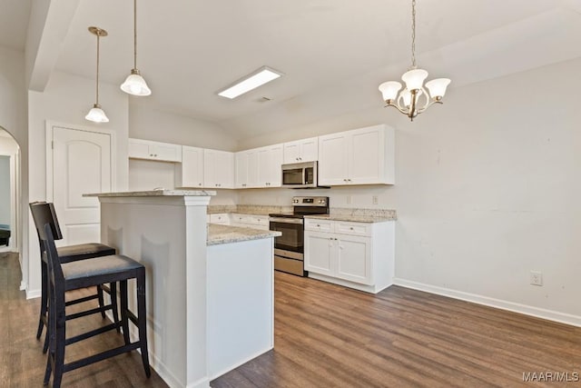 kitchen featuring white cabinets, pendant lighting, appliances with stainless steel finishes, and vaulted ceiling