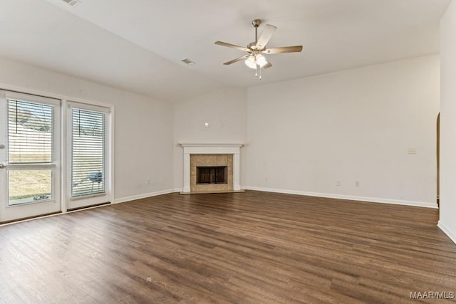 unfurnished living room with a tiled fireplace, ceiling fan, dark hardwood / wood-style flooring, and vaulted ceiling