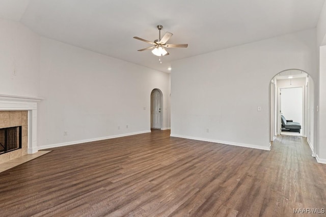 unfurnished living room with lofted ceiling, a tiled fireplace, ceiling fan, and dark hardwood / wood-style floors