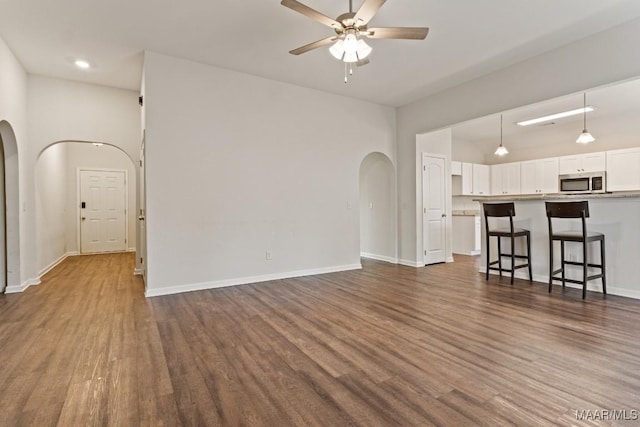 unfurnished living room with dark hardwood / wood-style floors and ceiling fan