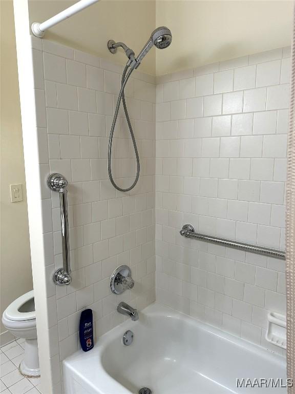 bathroom featuring tile patterned flooring, toilet, and tiled shower / bath