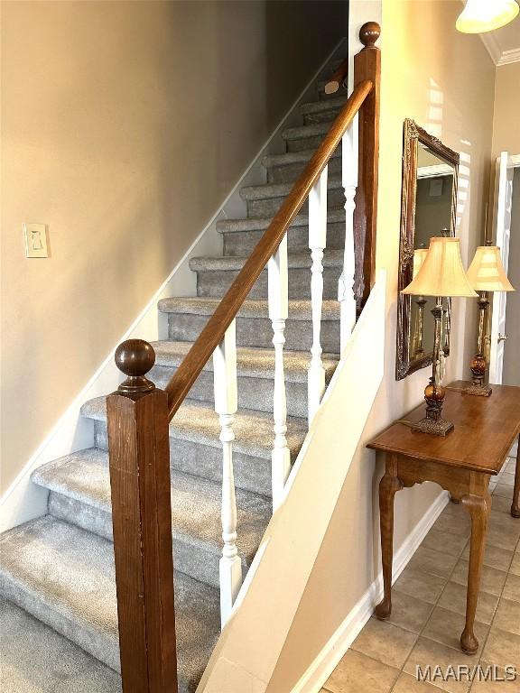 stairs featuring tile patterned flooring and crown molding