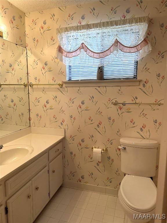 bathroom featuring tile patterned floors, vanity, toilet, and a textured ceiling