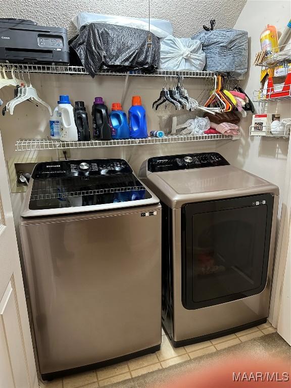 clothes washing area with light tile patterned flooring, a textured ceiling, and washing machine and clothes dryer