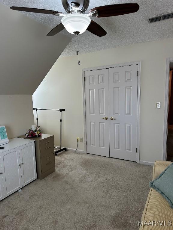 interior space featuring a textured ceiling, light carpet, and vaulted ceiling