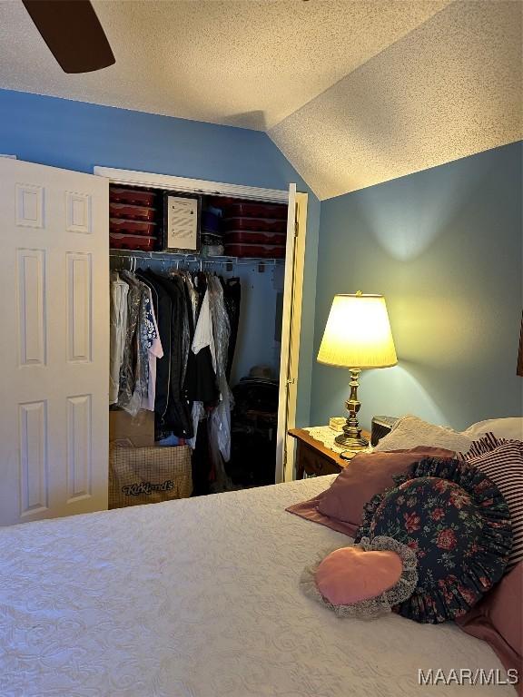 bedroom featuring a textured ceiling, a closet, and lofted ceiling