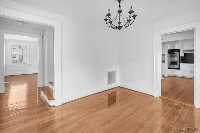 unfurnished dining area with crown molding, light hardwood / wood-style flooring, and a chandelier