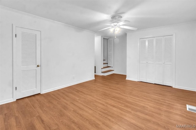 interior space featuring multiple closets, ceiling fan, crown molding, and light wood-type flooring