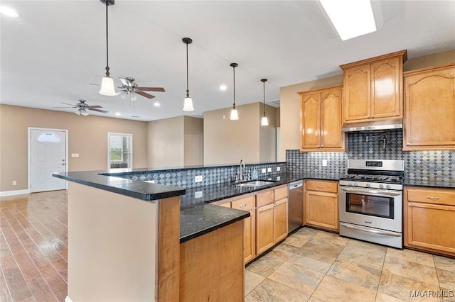 kitchen with kitchen peninsula, appliances with stainless steel finishes, dark stone counters, sink, and hanging light fixtures